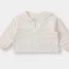A light beige knit sweater with a rounded neckline and long sleeves.