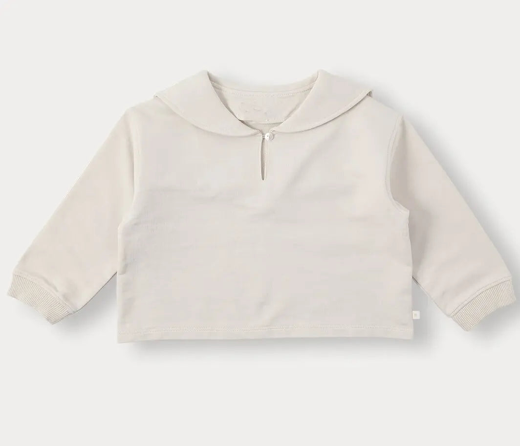 A light beige knit sweater with a rounded neckline and long sleeves.