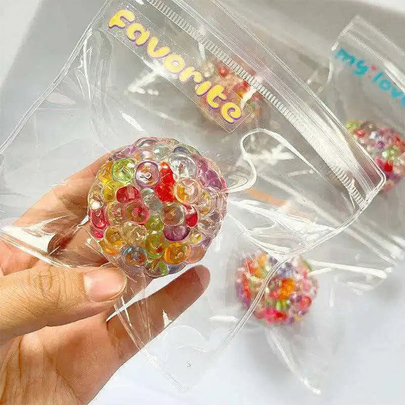 Eine Hand hält einen klaren Plastik-Kugelkalt-Spielball gefüllt mit farbenfrohen, funkelnden Perlen.