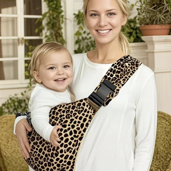 A woman holds a baby in an adjustable leopard print sling carrier.
