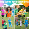 Children playing an egg spoon race game outdoors with colorful eggs and spoons.