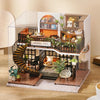 A clear acrylic puzzle kit of a miniature dollhouse featuring an interior cafe setting with wooden and dark accents.