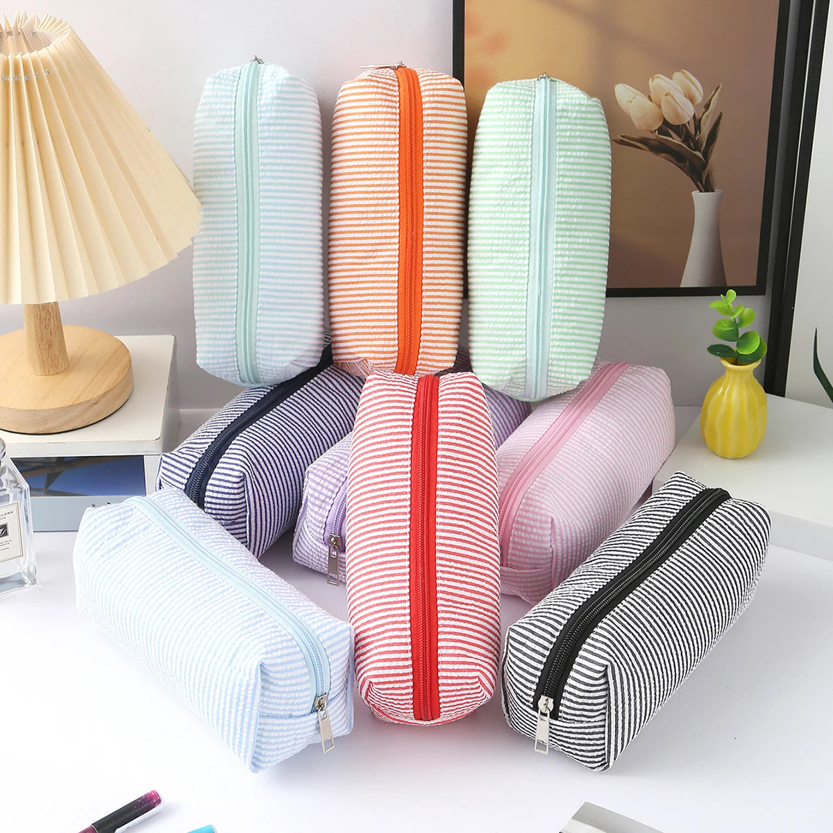 A collection of striped canvas pencil cases in various colors and patterns, including pink, orange, mint green, and black str