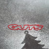 A red silhouette of the word GUTS is reflected on a wet, reflective surface.