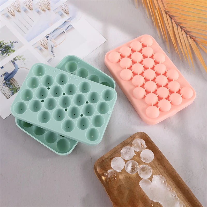 Pink silicone mold with multiple depressions for making soap or candles, next to a green version and some soap clusters.