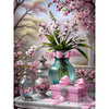 A pink and white floral arrangement with branches and blossoms displayed in a glass vase on a white surface.