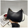 A black PU square crossbody bag with a gold zipper closure resting on a white surface.