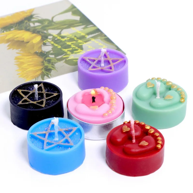 A collection of five scented candles in purple, green, blue, and red, featuring star and heart designs.