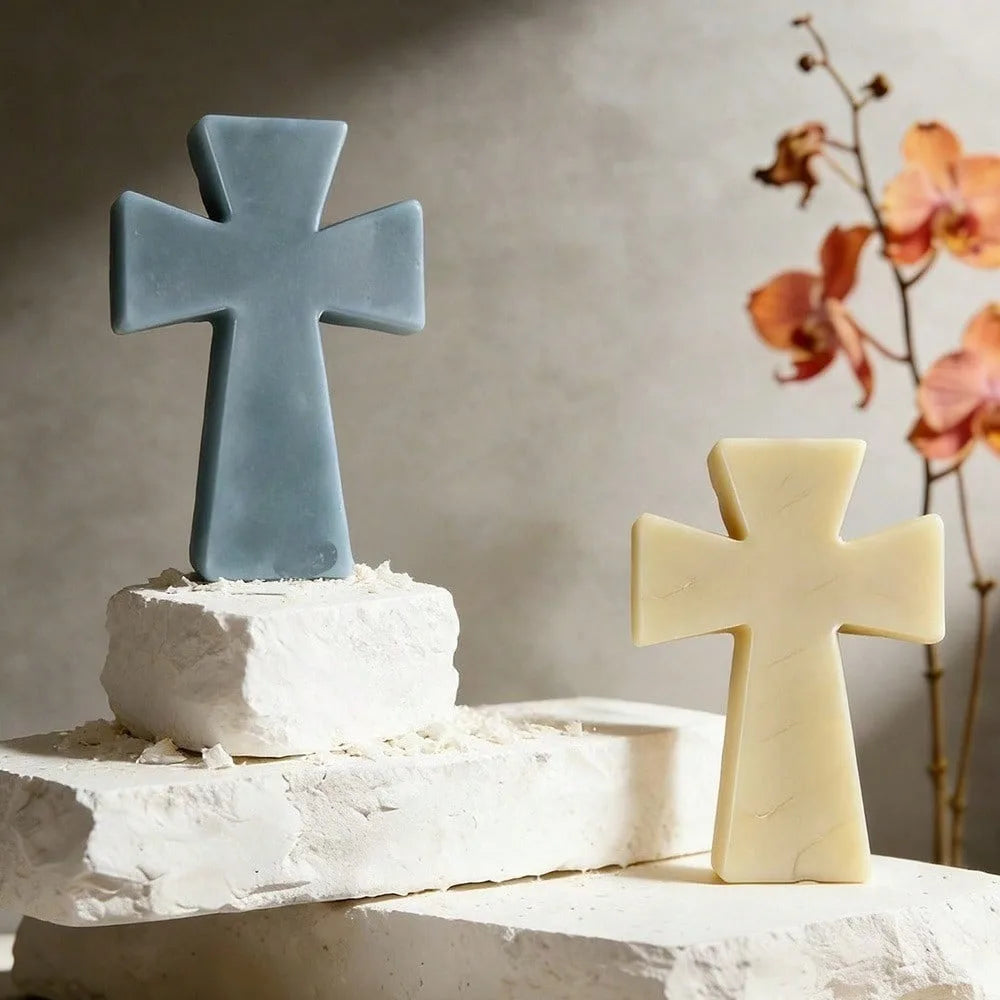 A light blue silicone cross mold sits on a white base next to a pale yellow cross mold.