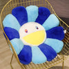 A large sunflower plush cushion with blue and purple petals and a white center is displayed in a gold wire basket.