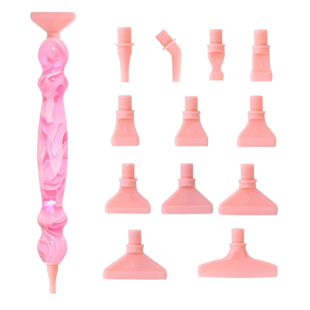 A pink Diamond Art pen kit showing a main body and twelve interchangeable tips arranged in a row.