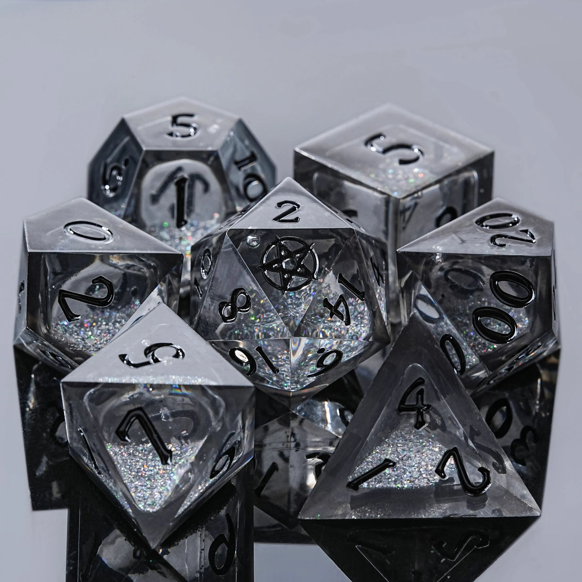 A collection of seven clear polyhedral dice, including a d20 and d10, resting on a dark surface.