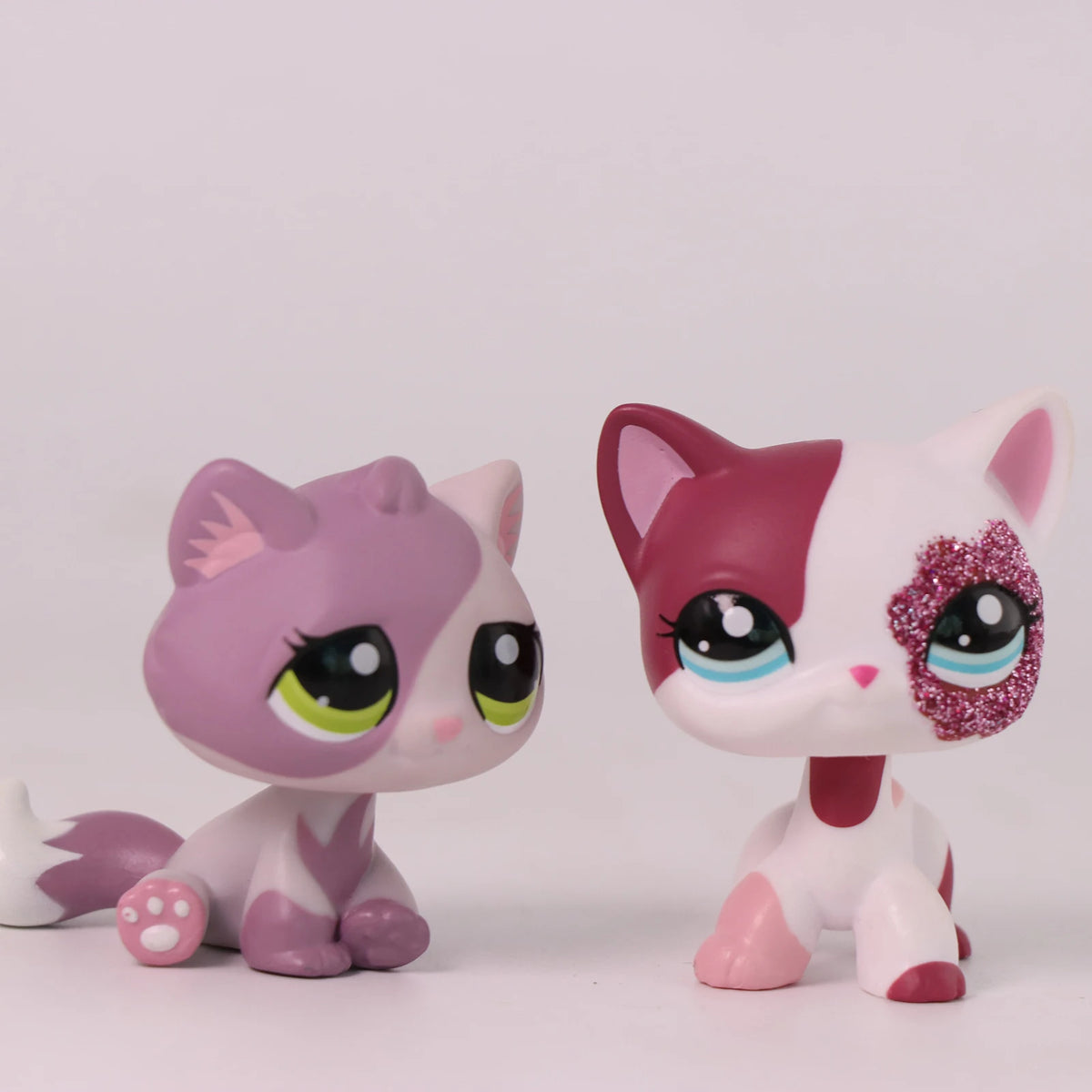A pink and white shorthair cat bobble head figurine with large eyes and pink ears.