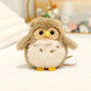 A fluffy, light brown cartoon bird plush with yellow beak and eyes, lying on a white surface.