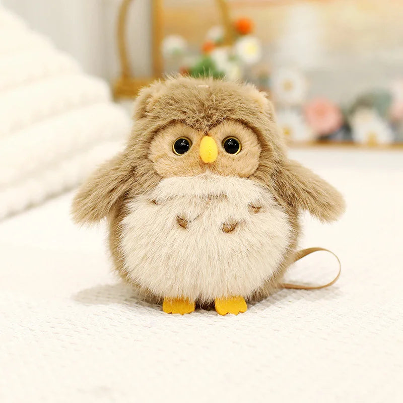 A fluffy, light brown cartoon bird plush with yellow beak and eyes, lying on a white surface.