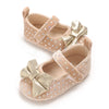Pair of light pink soft cotton baby walking shoes with gold bow details and dotted accents