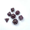 A collection of seven mini polyhedral dice in dark purple or maroon color scattered on a white background.