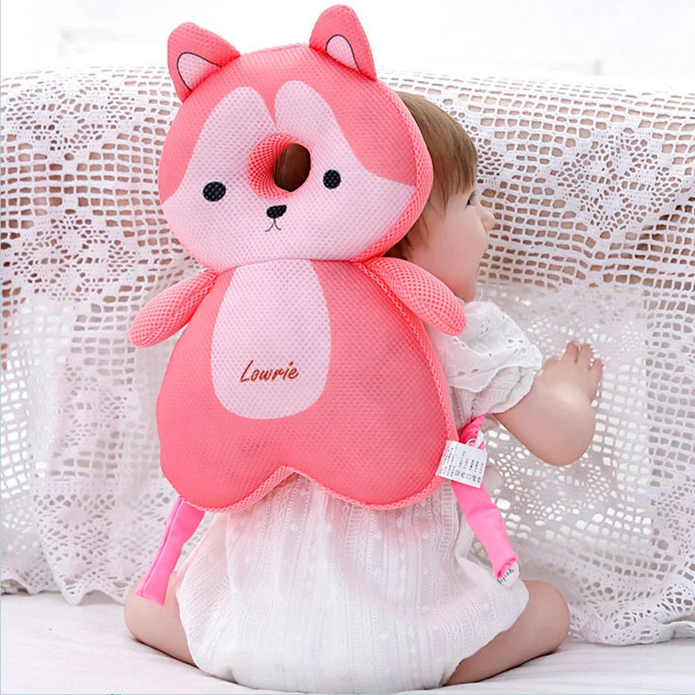 Sac à dos de protection en forme de renard rose pour bambin, assis sur une surface blanche.