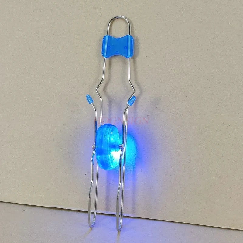 A retro magic rail twirler toy with a silver frame and blue plastic components glowing brightly.