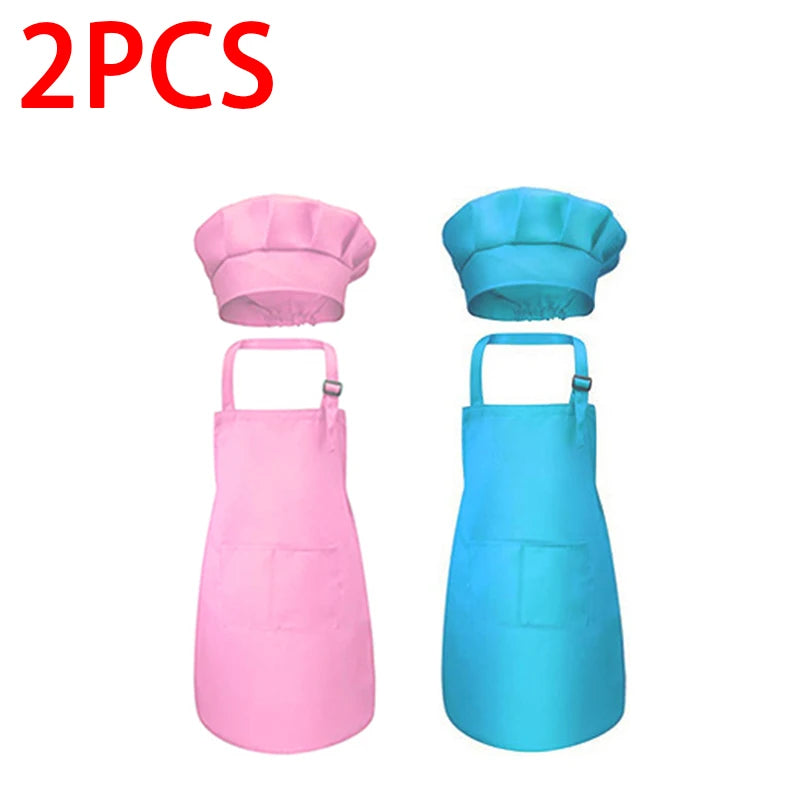 A set of two kids chef aprons and hats, one pink and one blue.