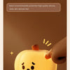 A close-up of a glowing yellow pumpkin LED night light with a face expression, resting on a brown surface.