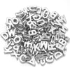 A pile of silver acrylic letter beads in various fonts and styles for DIY crafts