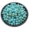 A pile of light blue and greenish-blue acrylic round beads for jewelry making.