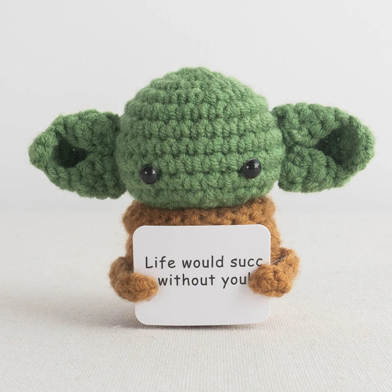 Handmade crochet pocket hug doll with green body and brown limbs featuring an inspirational slogan tag.