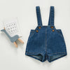 A navy blue denim romper for a toddler featuring chest pockets and straps, laid next to a card that reads Faith Hope Love.