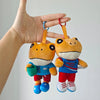 A plush toy of Bad Bunny El Sapo Concho with orange fur and blue clothing being held by a hand.