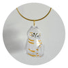 A clear, dog-shaped pet hair keepsake charm with striped markings suspended from a gold-colored cord.