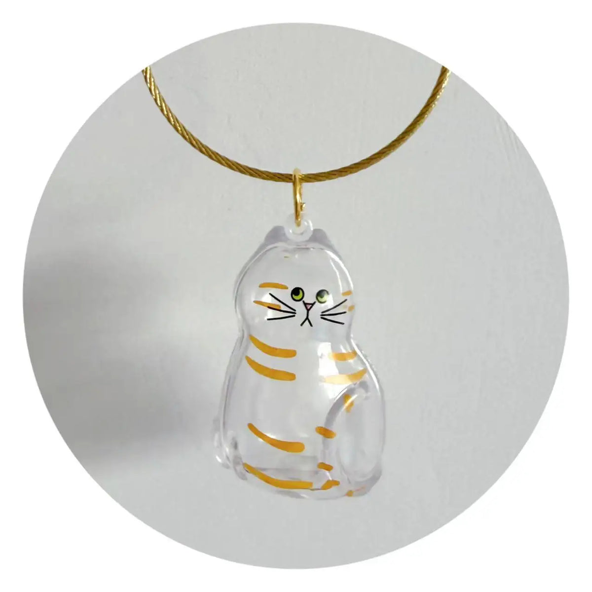 A clear, dog-shaped pet hair keepsake charm with striped markings suspended from a gold-colored cord.