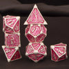 A set of seven pink and silver metal polyhedral dice for tabletop gaming