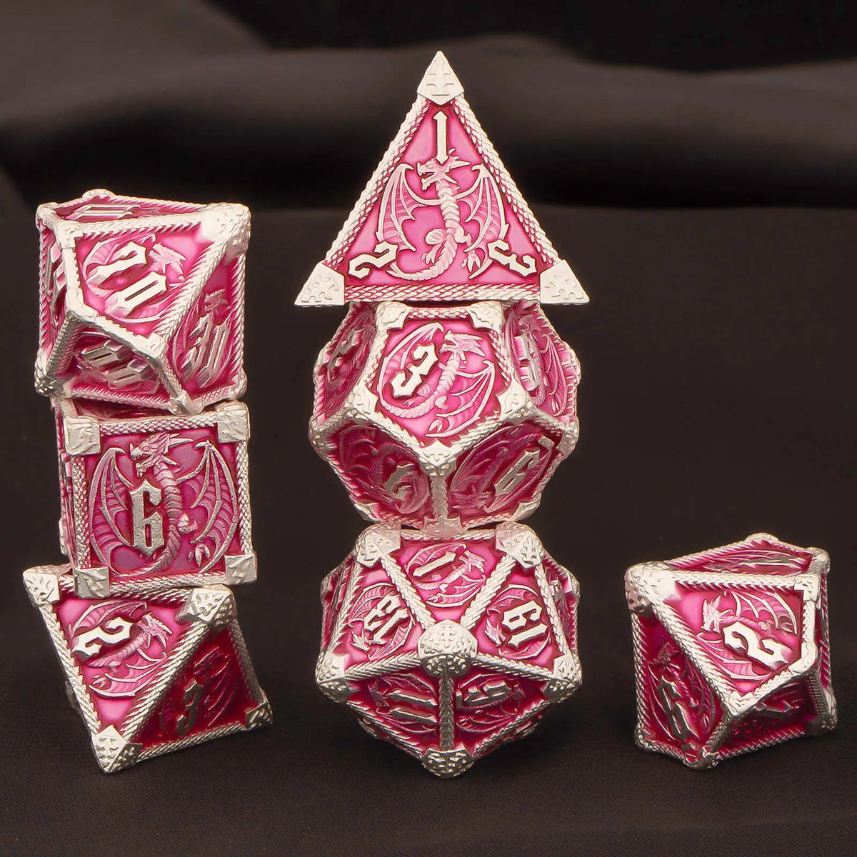 A set of seven pink and silver metal polyhedral dice for tabletop gaming