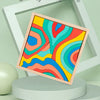 A colorful wooden puzzle featuring abstract rainbow lines displayed in a white picture frame.