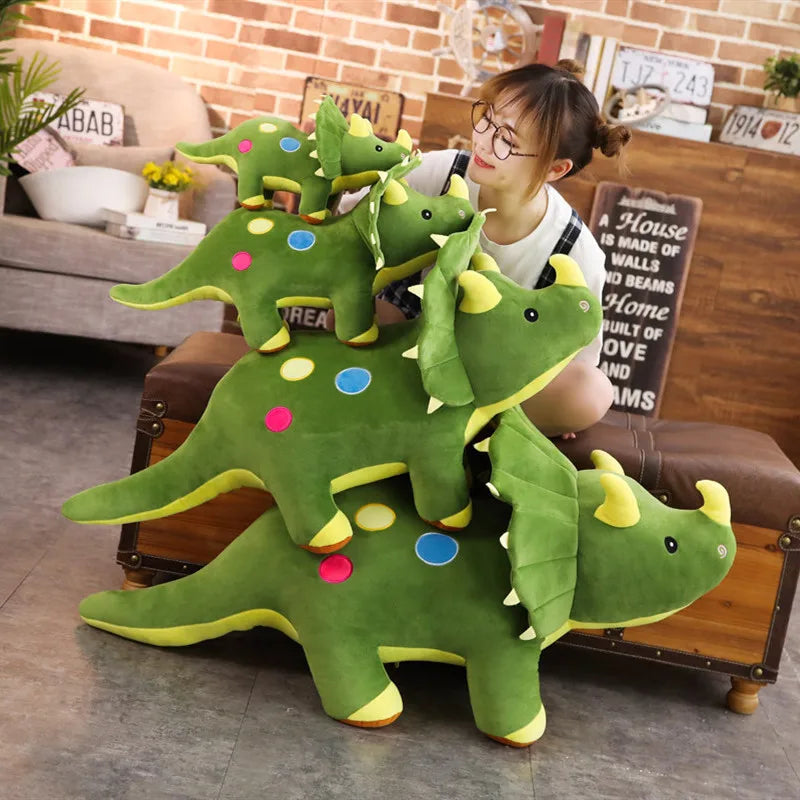 A green dinosaur plush toy with yellow accents is displayed on a wooden surface next to a woman.