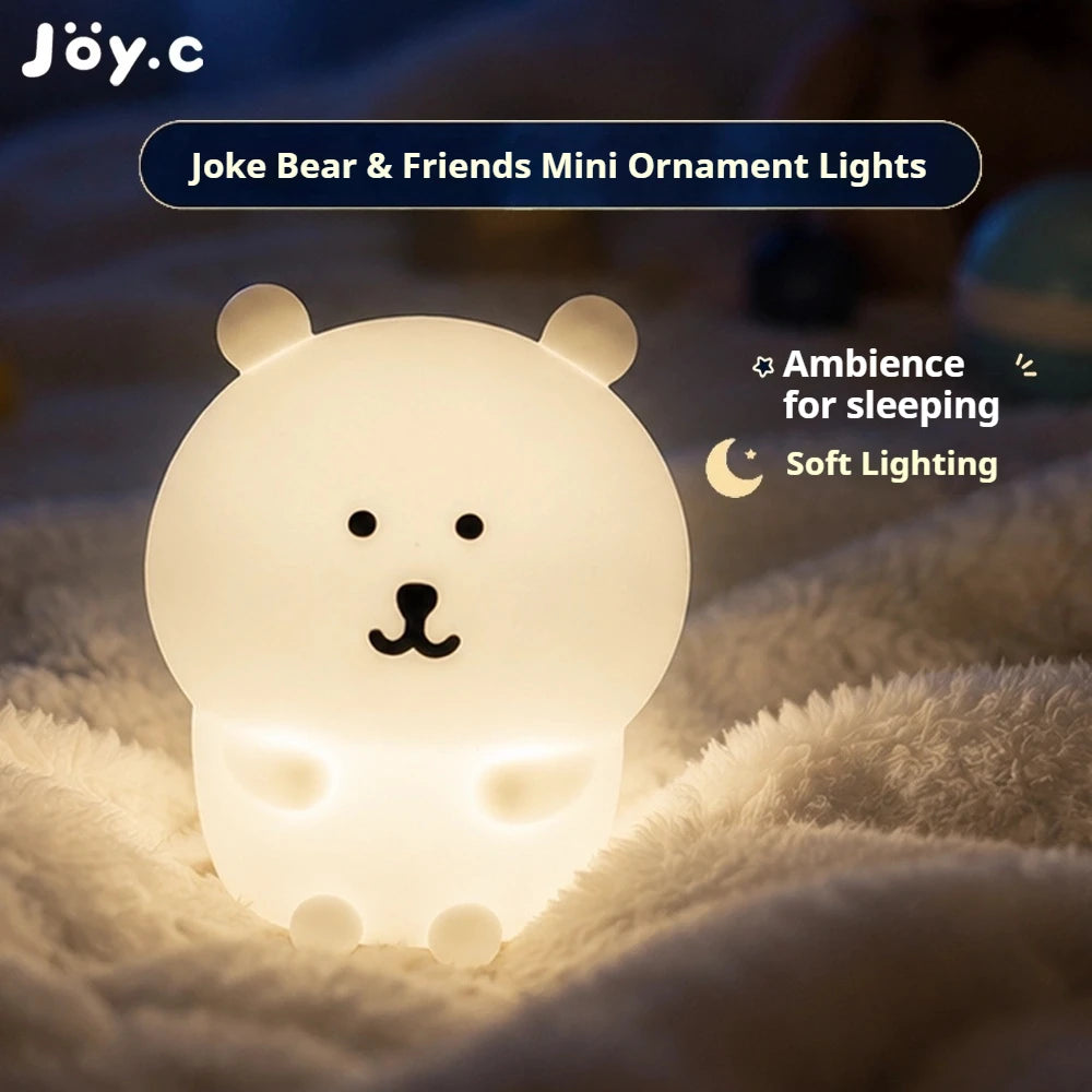 A white silicone bear ornament light emitting soft, warm glow on a fluffy surface for sleeping ambiance.