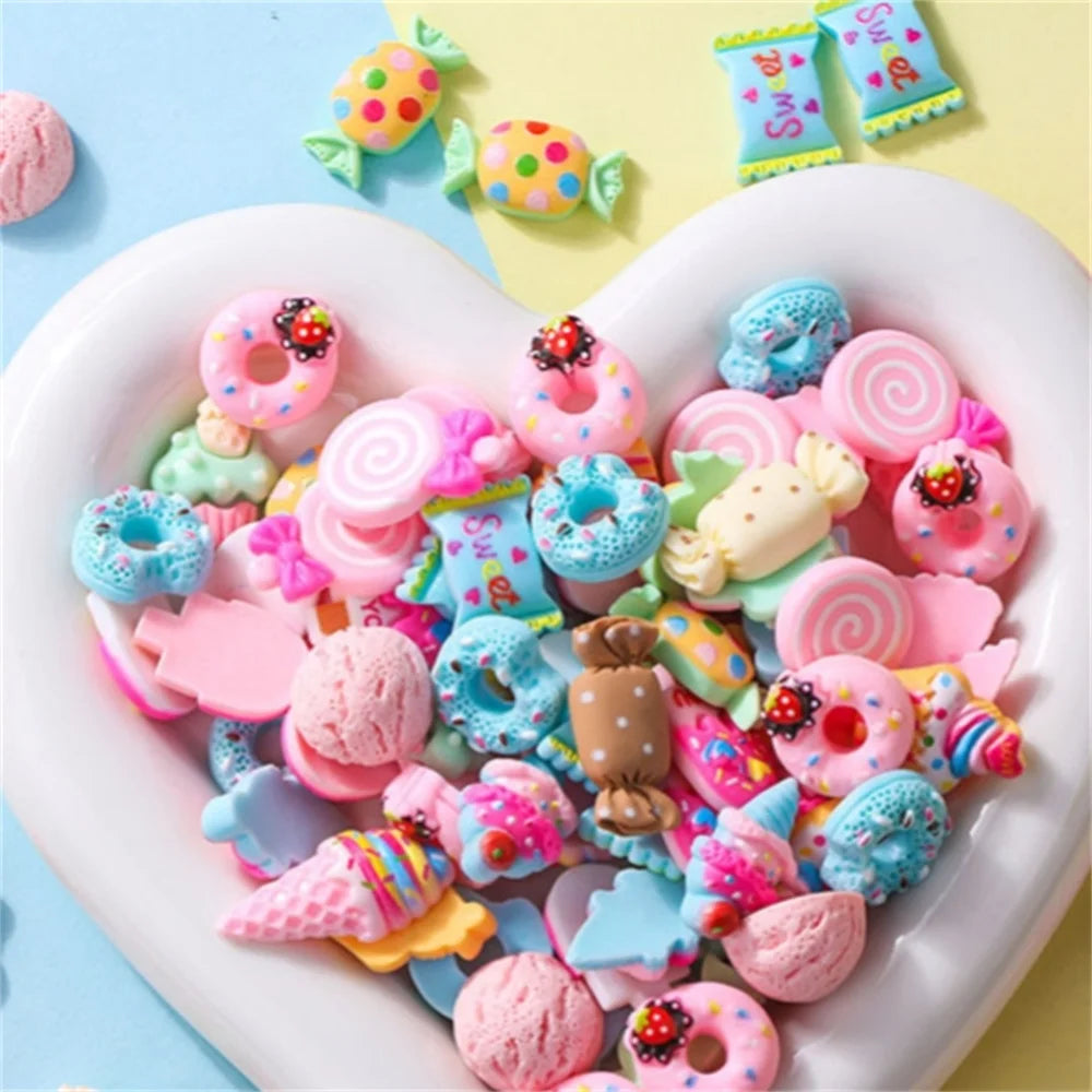 A heart-shaped dish filled with assorted pink, blue, and yellow candy resin flatbacks for DIY crafts.
