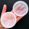 A hand holds two clear silicone molds for resin crafting, showing the circular shape and texture.