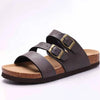 A pair of dark brown suede cork mules with gold-toned buckles and arch support.