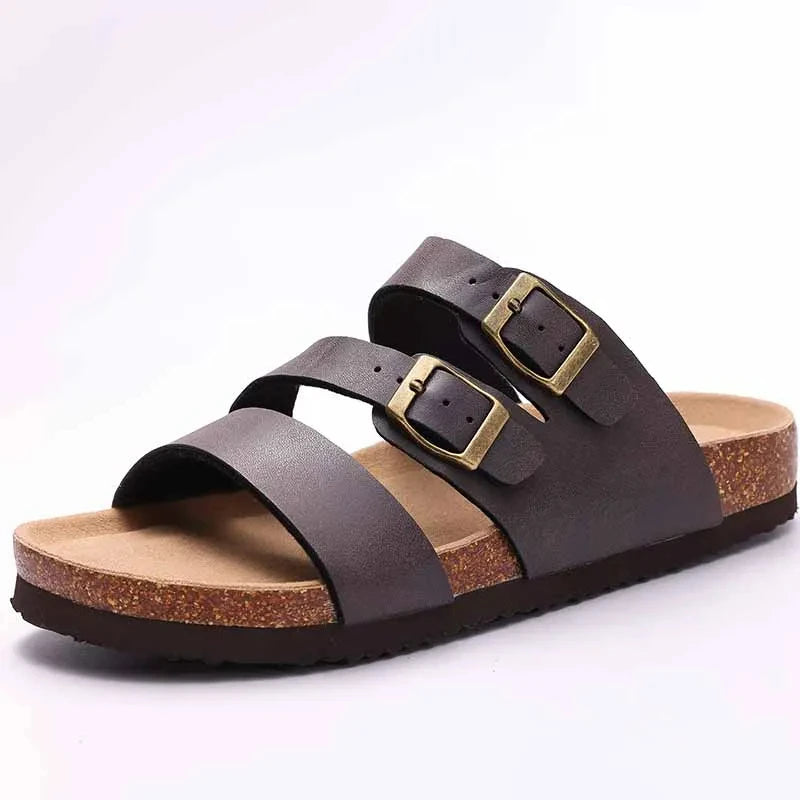 A pair of dark brown suede cork mules with gold-toned buckles and arch support.
