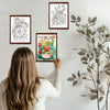 A woman is shown coloring a page from an adult coloring book featuring detailed floral designs.