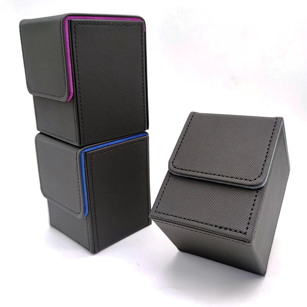 A stack of dark gray leather deck boxes, some with purple and blue accents, are displayed on a white surface.