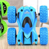 A blue four-wheel drive stunt car with black and light blue accents and rubber tires is shown on a wooden surface.