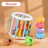 A colorful round wooden shape-sorting toy for toddlers featuring various colored wooden shapes and a small green piece.