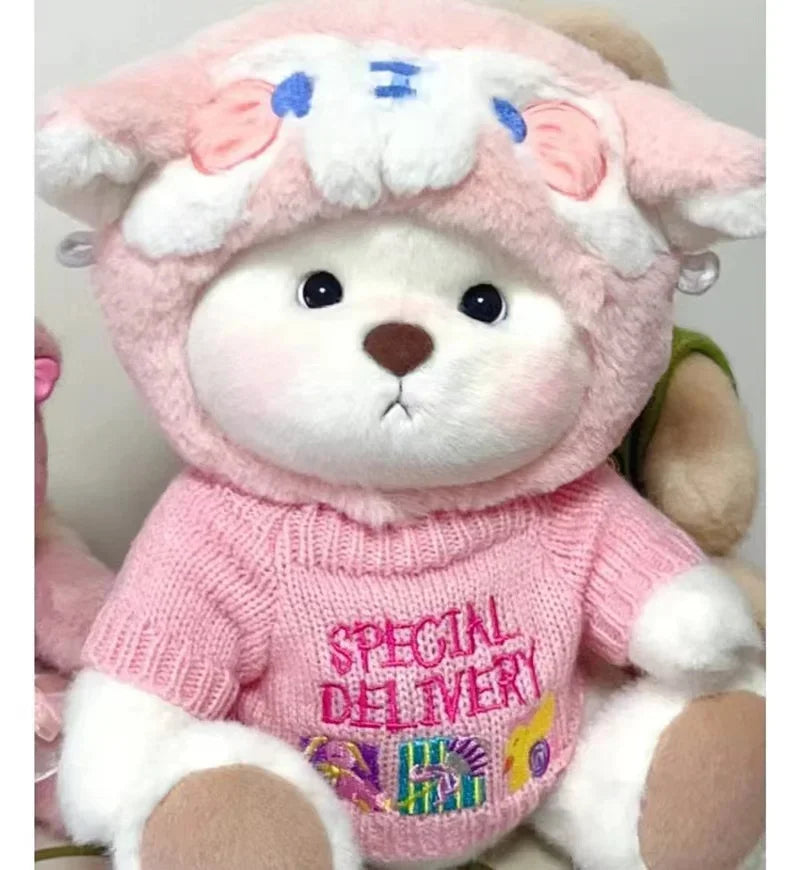 A pink and white fluffy teddy bear plush with a pink sweater featuring a special delivery design.