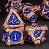 A set of seven polyhedral metal dice in gold and blue colors resting on a dark surface.