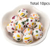 A bowl filled with ten white silicone beads printed with colorful floral patterns for DIY jewelry making