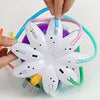 A hand is assembling an octopus water spray sprinkler for kids, showing the white and colored nozzles and tubing.
