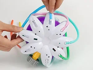 A hand is assembling an octopus water spray sprinkler for kids, showing the white and colored nozzles and tubing.